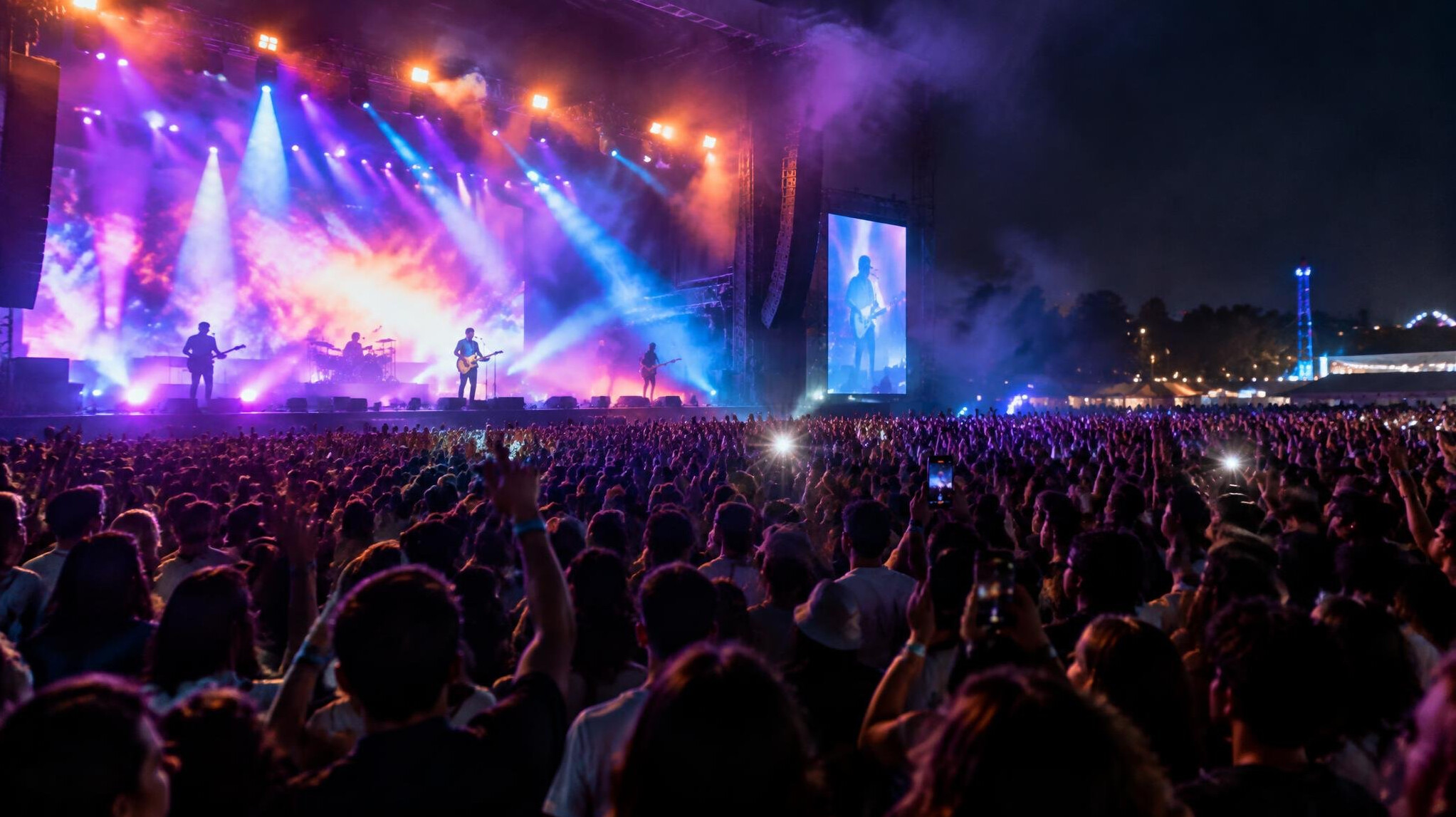 Concert crowd with stage lights and camera flashes